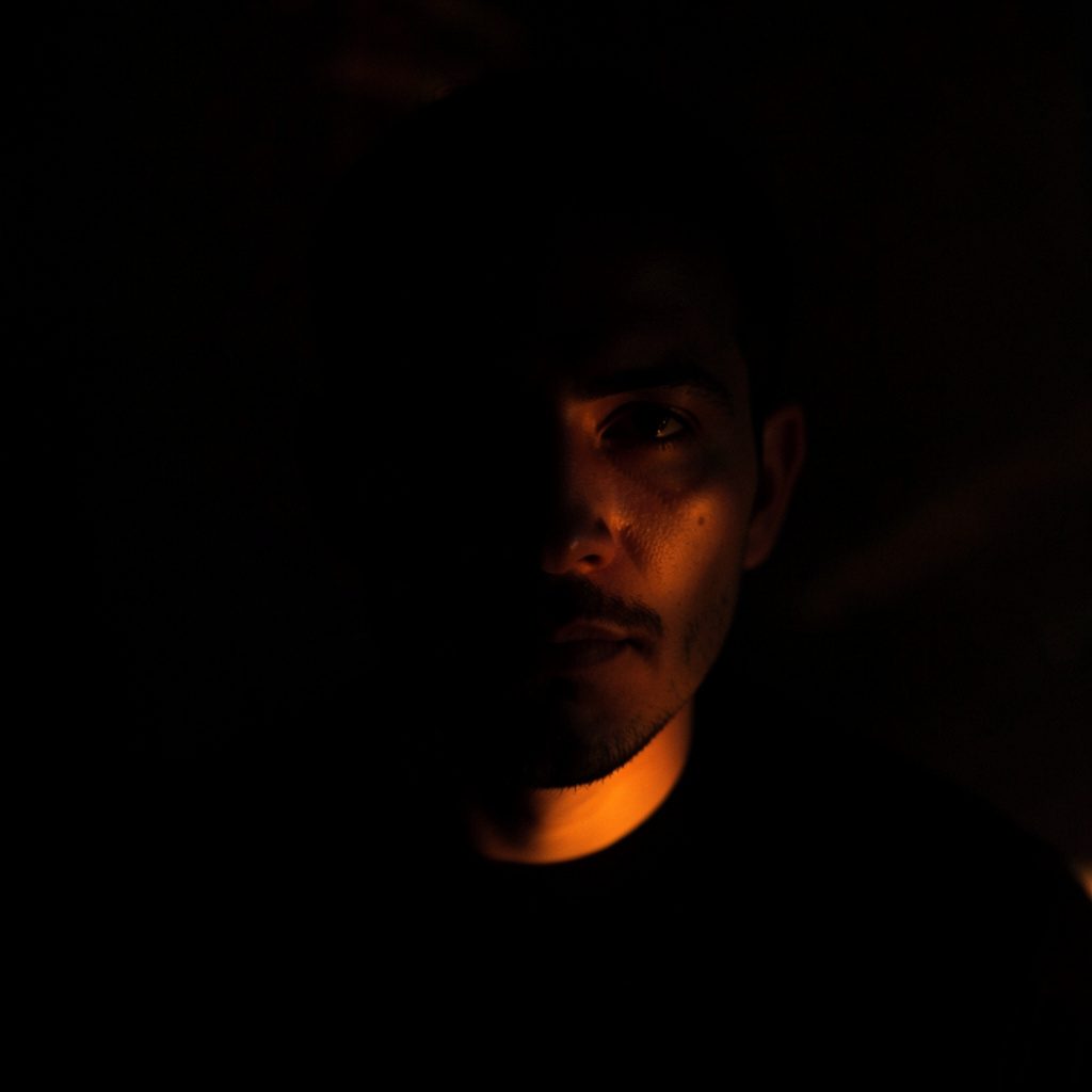 Dark, dramatic photograph symbolizing high-profile news coverage, with deep shadow and a single point of light